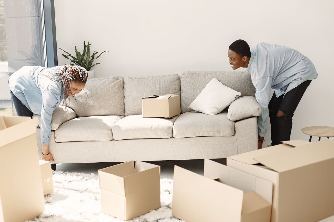 services-01 Happy couple setting up a sofa in their new home surrounded by moving boxes.